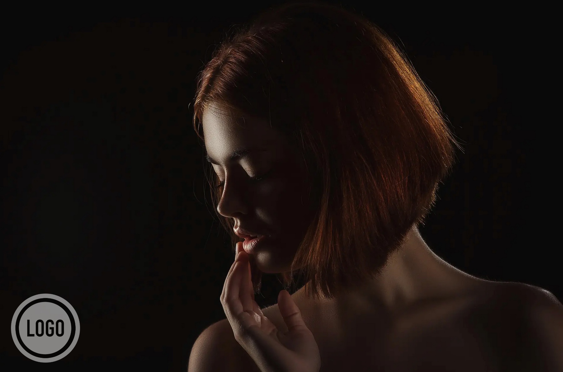 Low-key portrait with a circular logo watermark placed in the lower corner